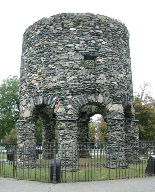 Squat round tower of grey stone over 8 arches